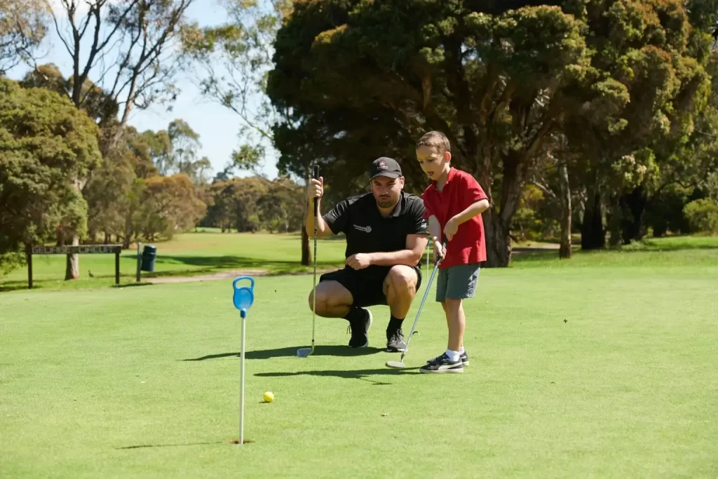 Child having a golf lesson with male golfer